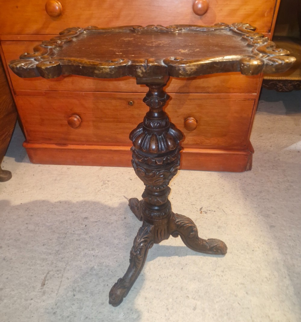 A late Victorian dark oak occasional table featuring a shaped moulded top, a heavily turned gadrooned column, and carved tripod cabriole legs.