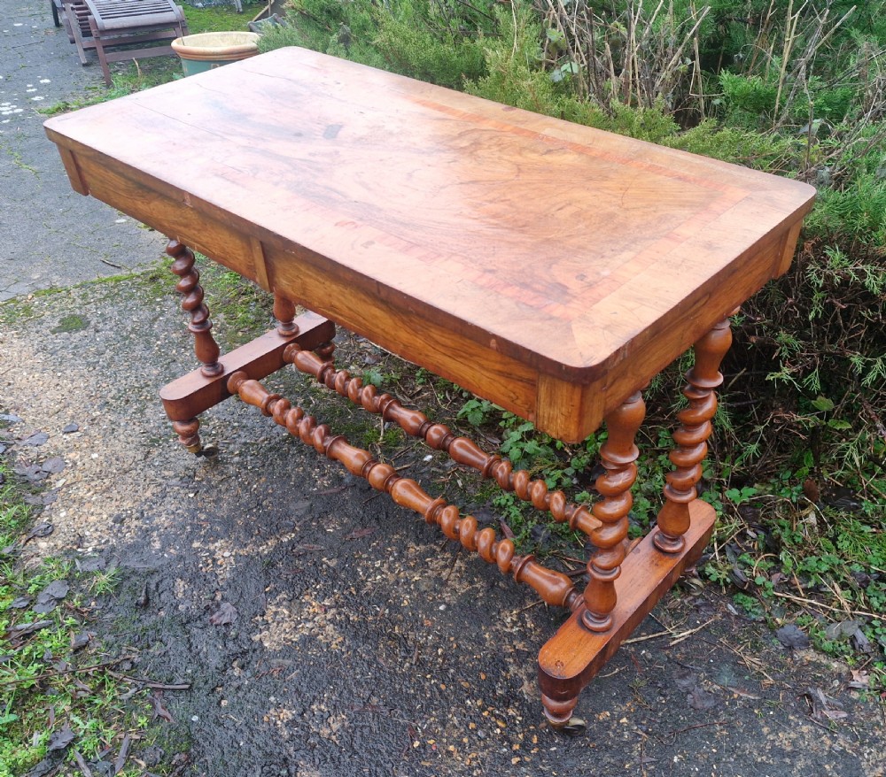 A Victorian walnut side table featuring a rectangular inlaid top, two frieze drawers, and turned barley twist legs connected by stretchers on brass castors.