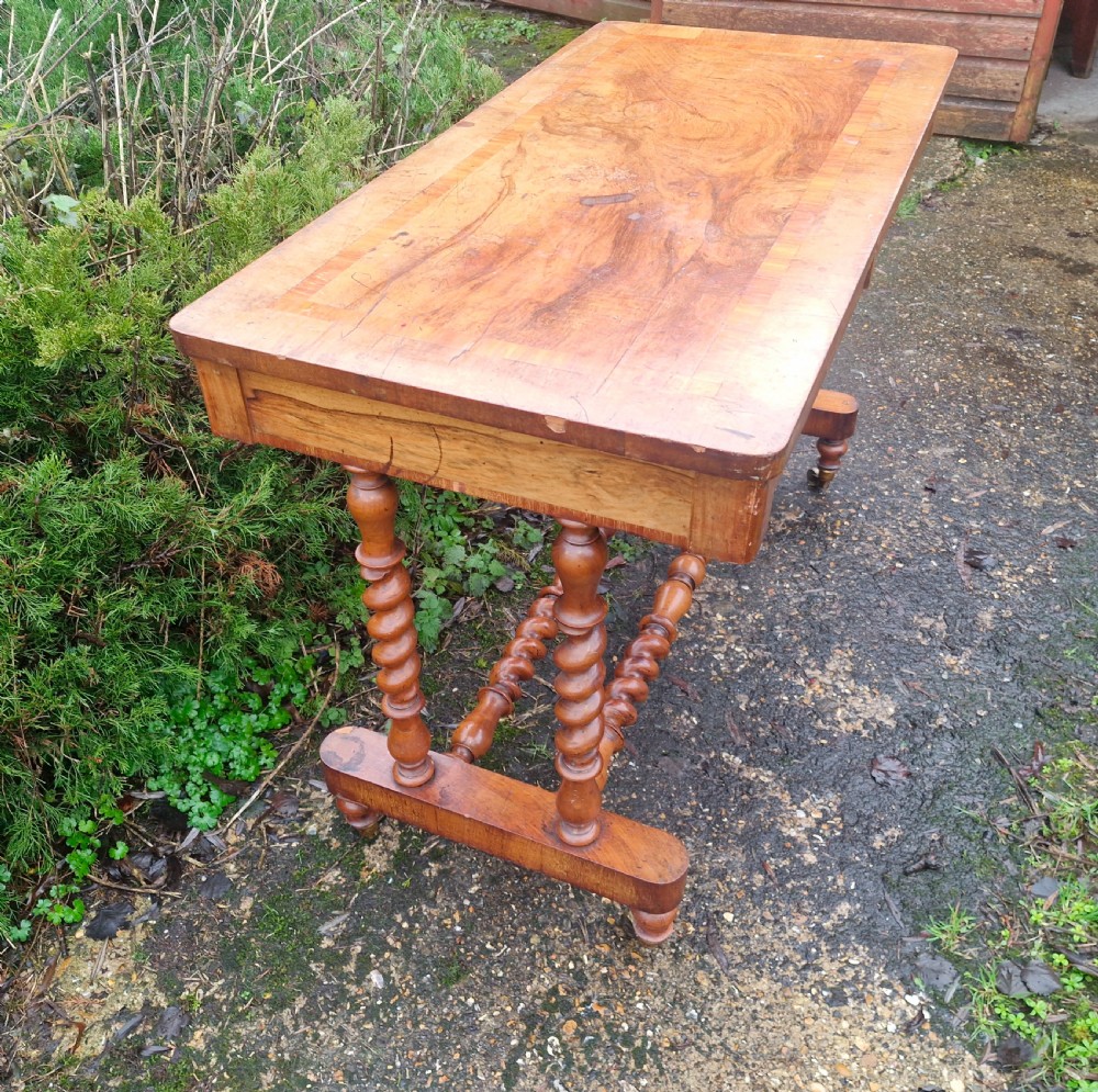 A Victorian walnut side table featuring a rectangular inlaid top, two frieze drawers, and turned barley twist legs connected by stretchers on brass castors. View V