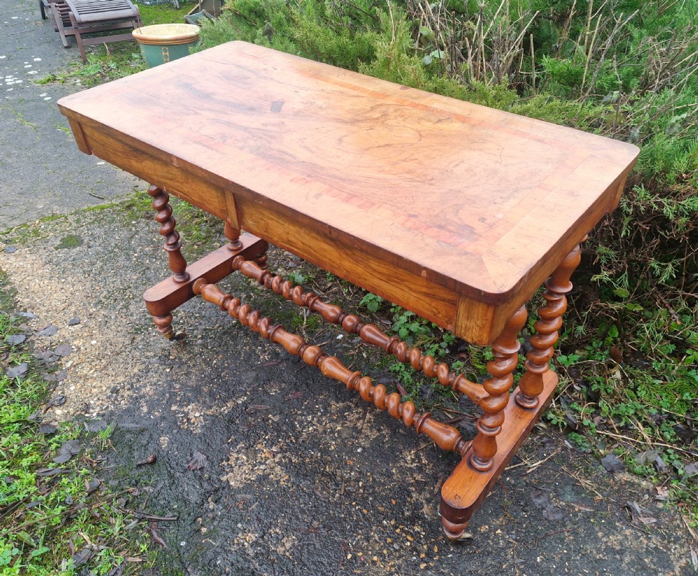 A Victorian walnut side table featuring a rectangular inlaid top, two frieze drawers, and turned barley twist legs connected by stretchers on brass castors. View VII