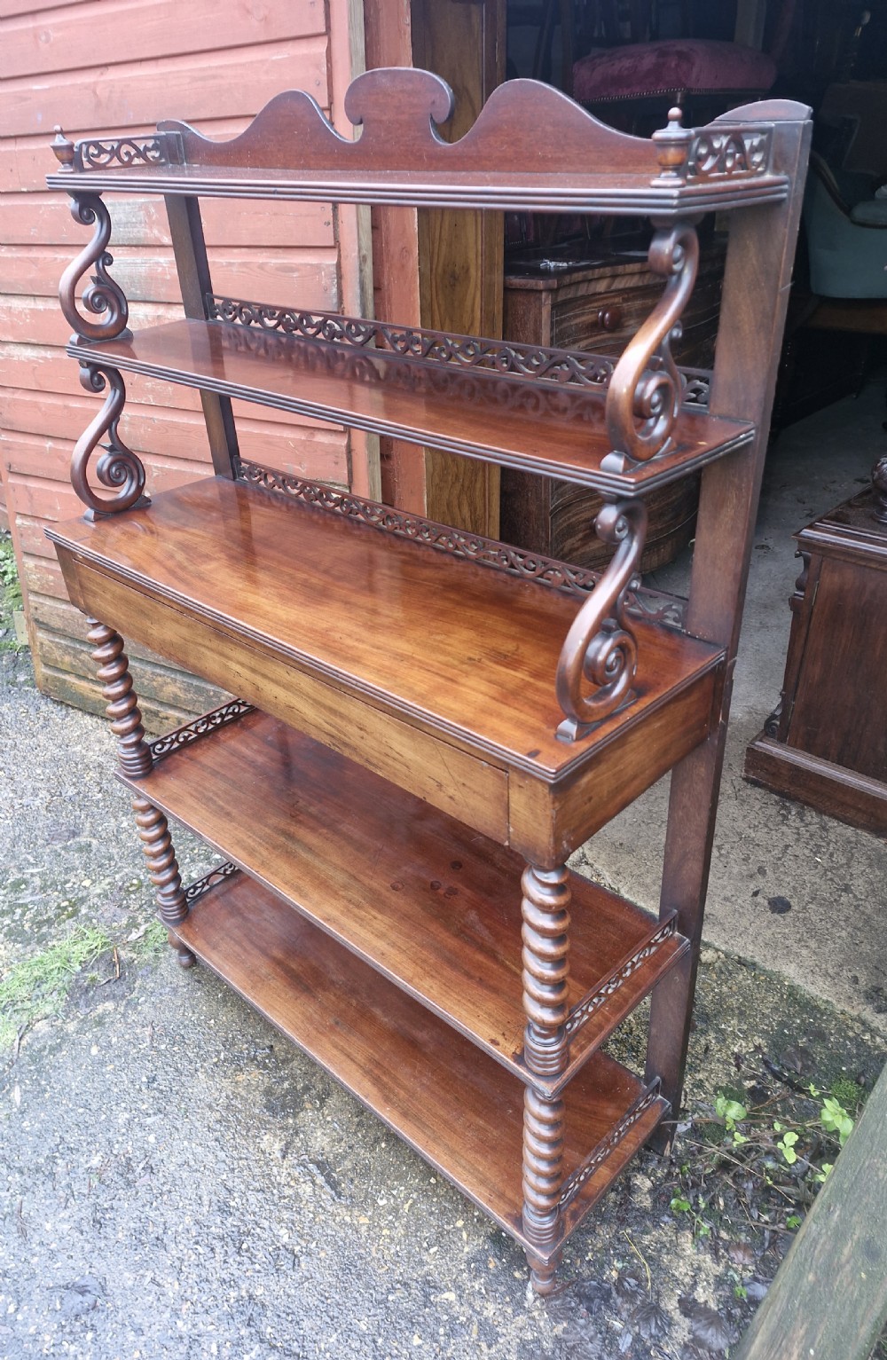 A mid-19th-century mahogany etagere featuring multiple open tiers, decorative fretwork galleries, carved scroll supports, lower barley-twist columns, and a central single drawer.