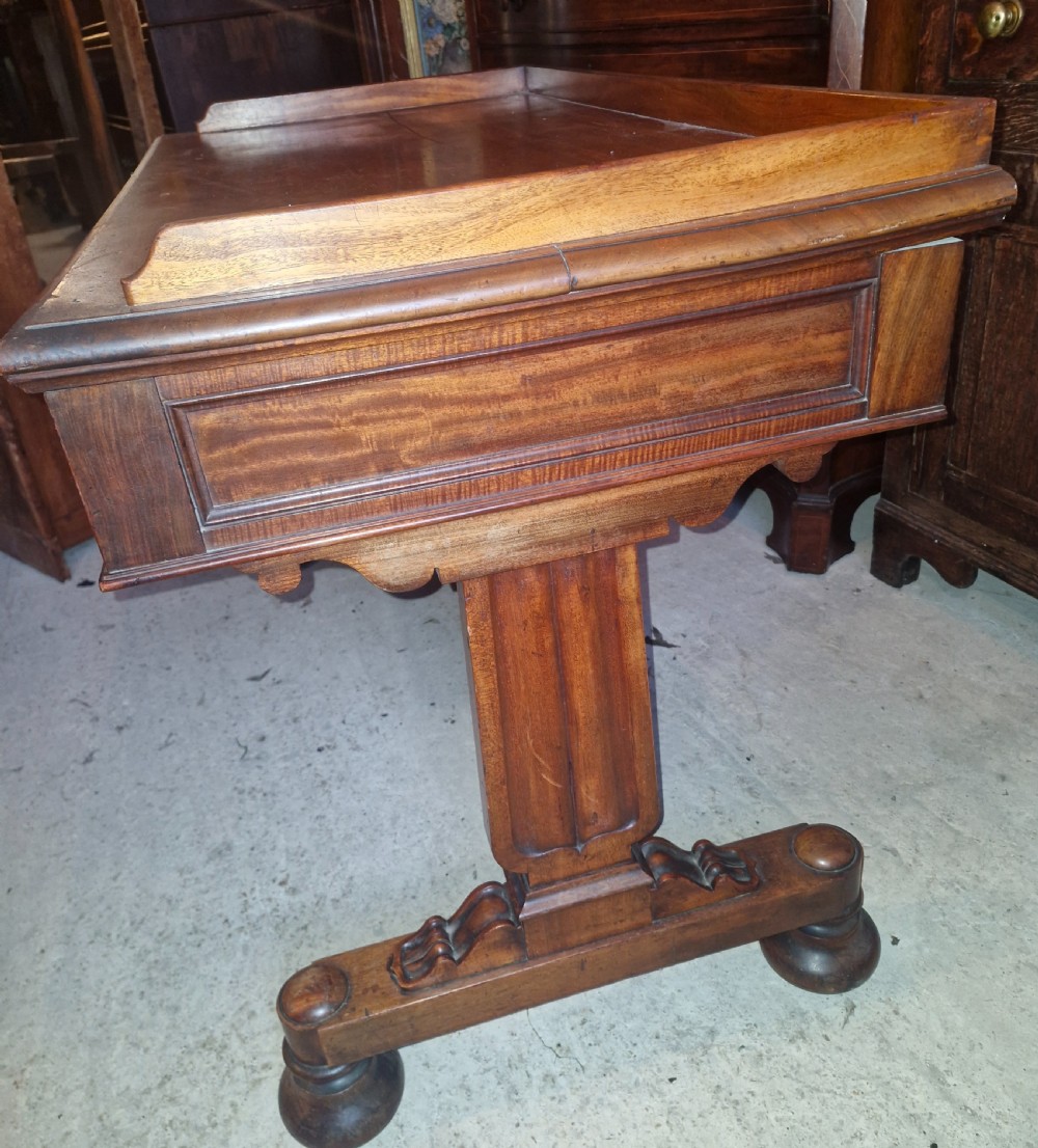 An early Victorian mahogany writing table featuring a low gallery rim, three frieze drawers with turned wooden knobs, and a trestle base with thick turned feet. View III