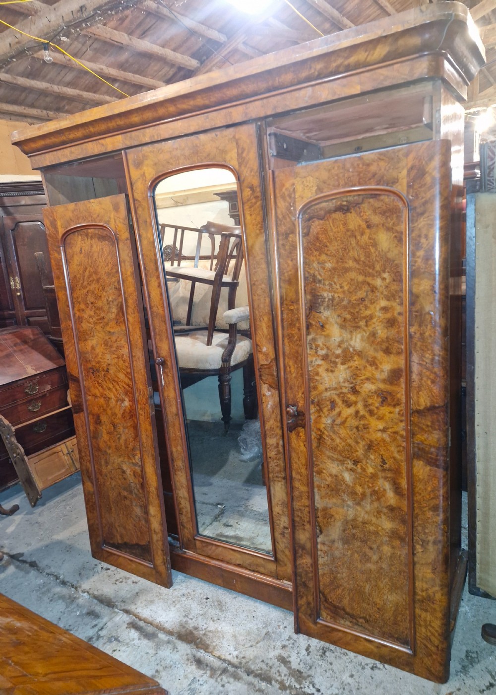 A nineteenth-century Victorian triple wardrobe crafted from figured burr walnut, featuring a central mirrored door flanked by two panelled timber doors. View II