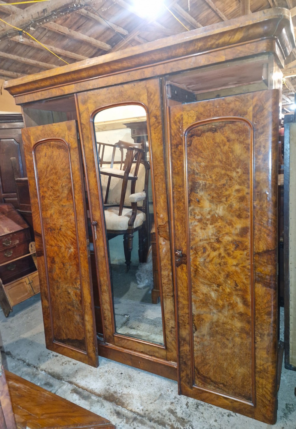 A nineteenth-century Victorian triple wardrobe crafted from figured burr walnut, featuring a central mirrored door flanked by two panelled timber doors. View III