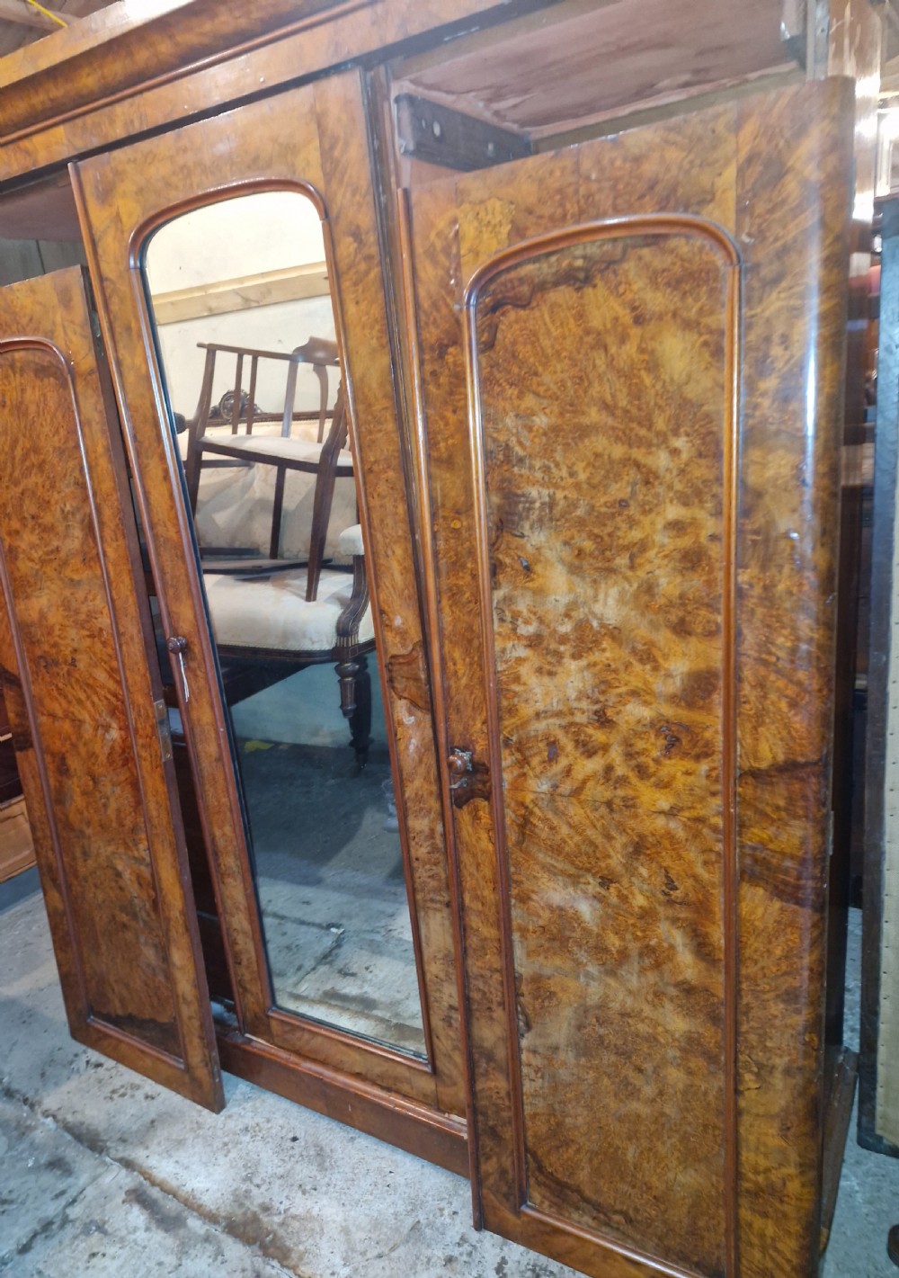 A nineteenth-century Victorian triple wardrobe crafted from figured burr walnut, featuring a central mirrored door flanked by two panelled timber doors. View IV