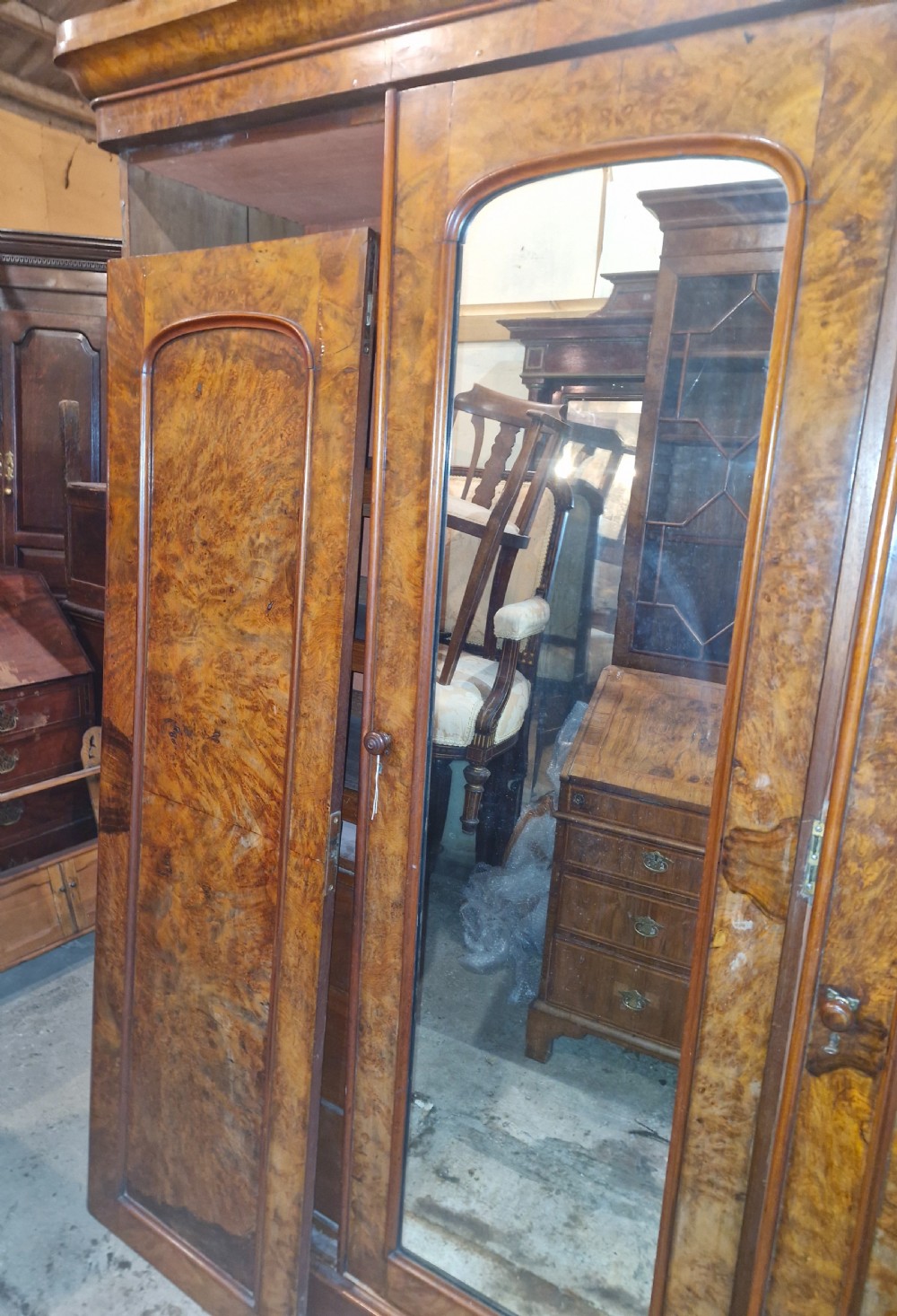 A nineteenth-century Victorian triple wardrobe crafted from figured burr walnut, featuring a central mirrored door flanked by two panelled timber doors. View VII