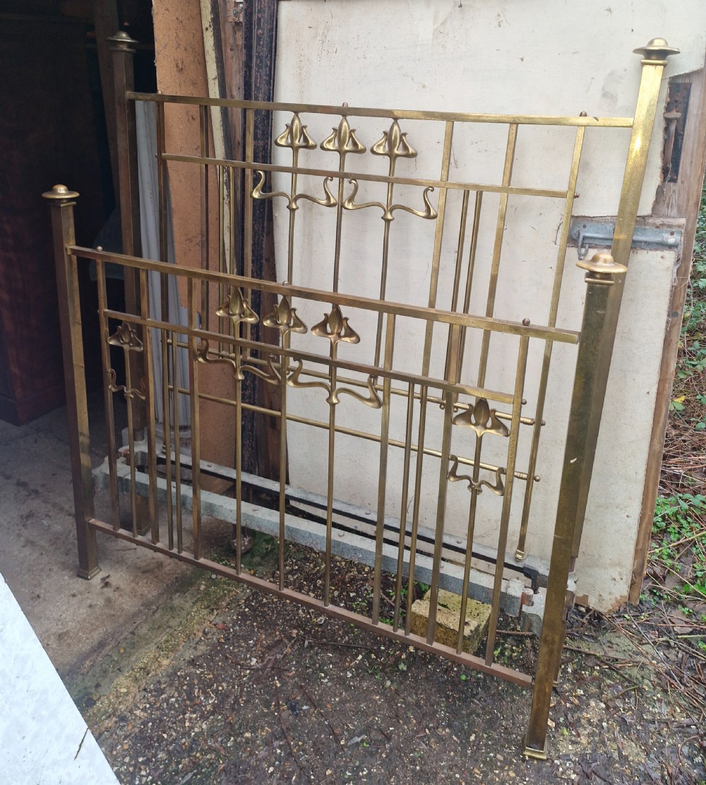 An Art Nouveau brass double bed frame with headboard, footboard, and original side irons featuring stylized floral motifs. View VI