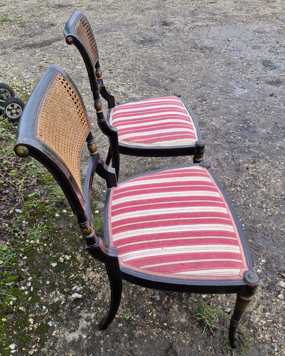 Pair of black painted antique side chairs featuring woven cane backrests, gold floral hand-painted details, and red and cream striped upholstered seats. View IV