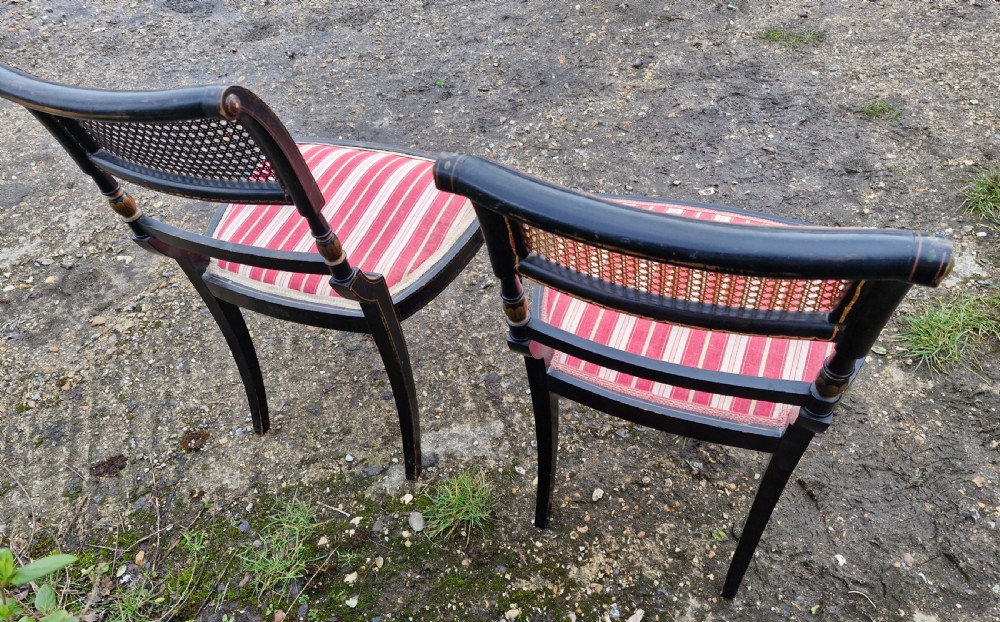 Pair of black painted antique side chairs featuring woven cane backrests, gold floral hand-painted details, and red and cream striped upholstered seats. View V