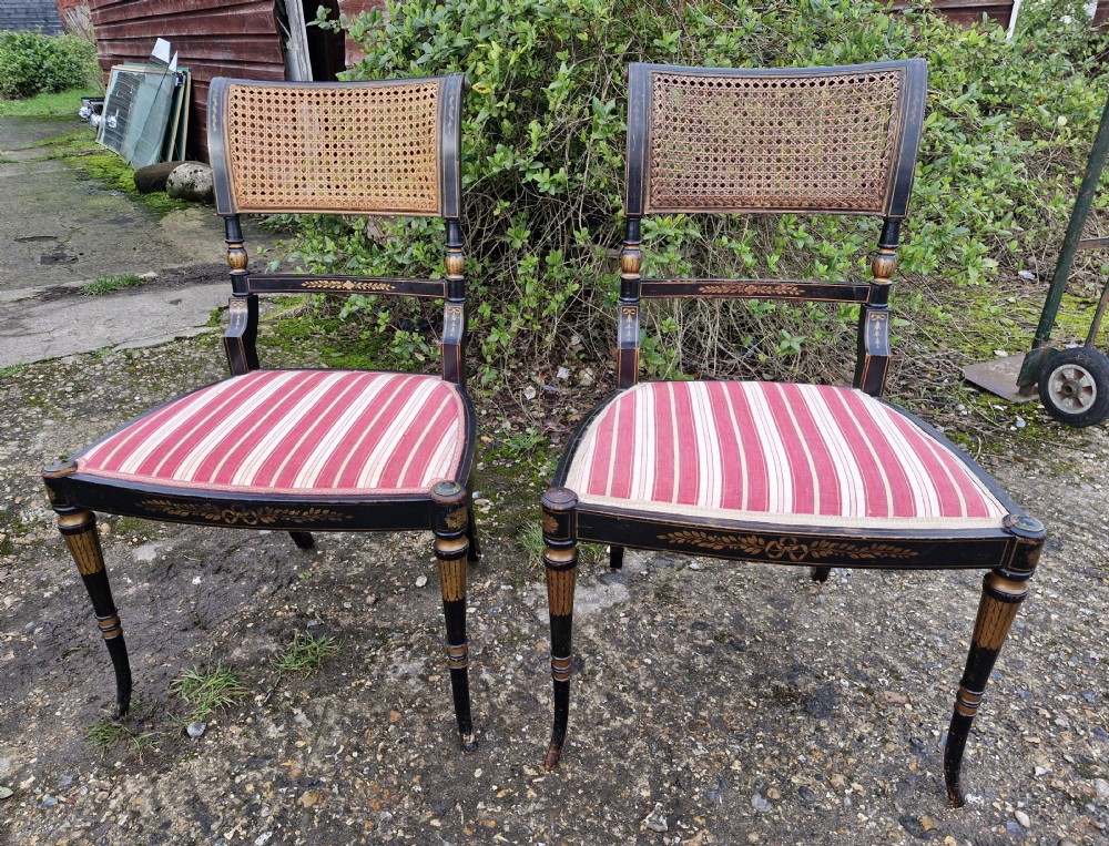 Pair of black painted antique side chairs featuring woven cane backrests, gold floral hand-painted details, and red and cream striped upholstered seats. View VII