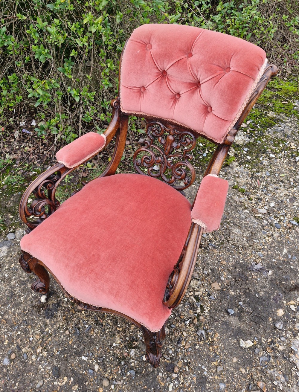 A Victorian carved walnut armchair upholstered in rose pink button-tufted velvet with pierced scrollwork detailing and cabriole legs. View II