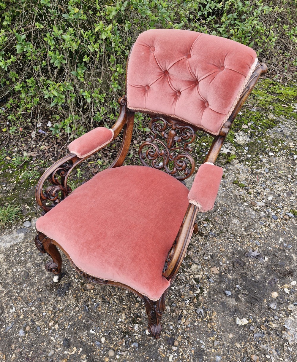 A Victorian carved walnut armchair upholstered in rose pink button-tufted velvet with pierced scrollwork detailing and cabriole legs. View III