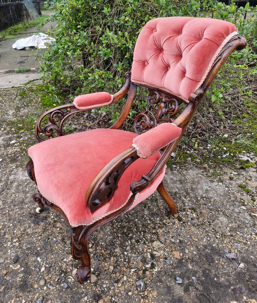 A Victorian carved walnut armchair upholstered in rose pink button-tufted velvet with pierced scrollwork detailing and cabriole legs. View IV