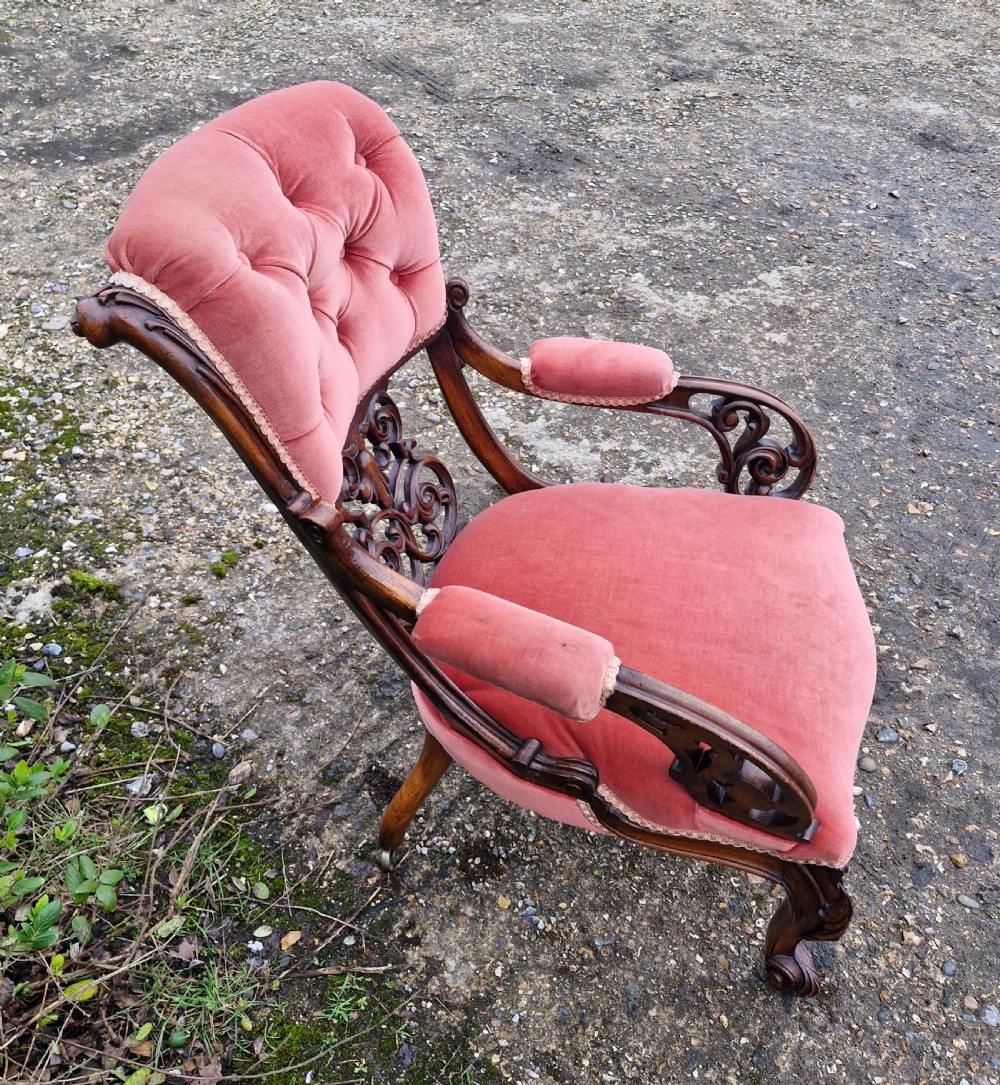 A Victorian carved walnut armchair upholstered in rose pink button-tufted velvet with pierced scrollwork detailing and cabriole legs. View VI