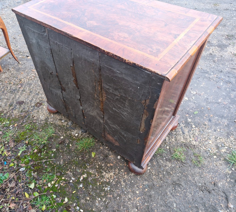 An antique walnut chest of four drawers featuring highly figured burr veneers, inlaid crossbanding, metal handles, and turned bun feet. View III