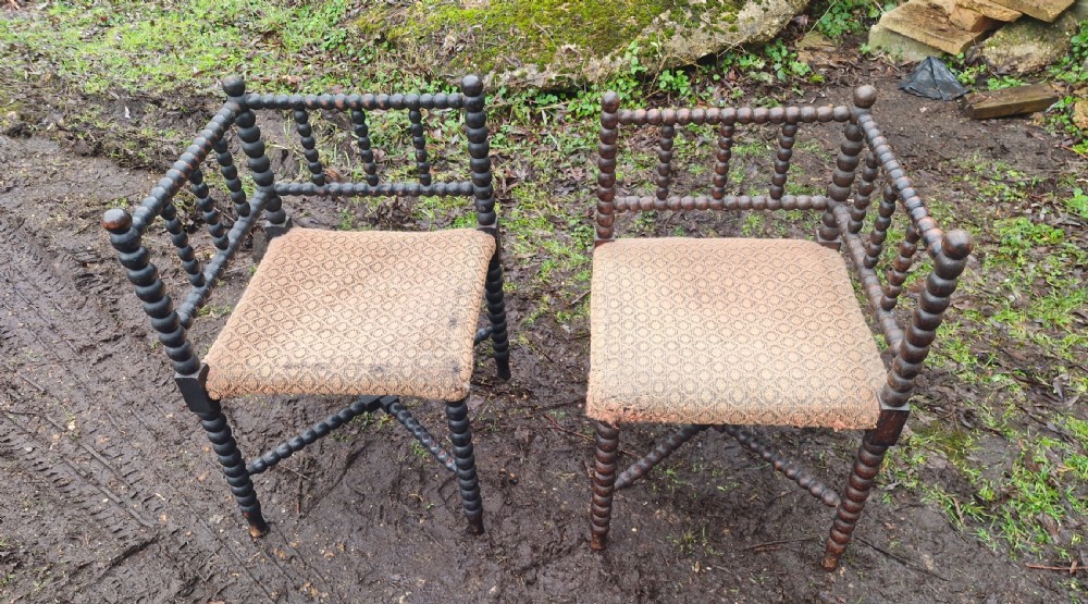 A pair of dark wood bobbin-turned corner chairs featuring patterned fabric seats and crossed lower stretchers. View II