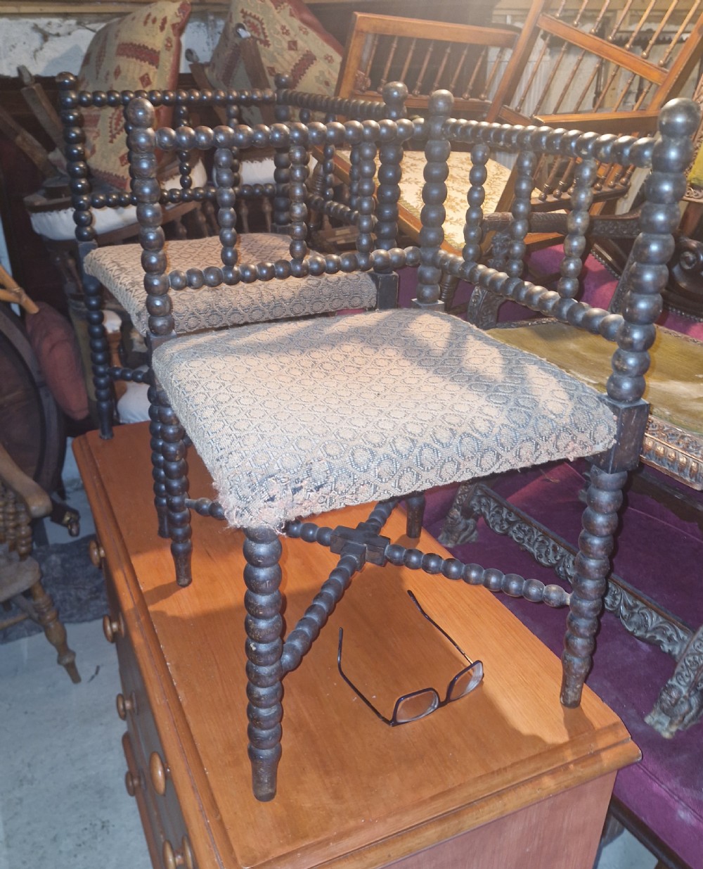 A pair of dark wood bobbin-turned corner chairs featuring patterned fabric seats and crossed lower stretchers. View IV