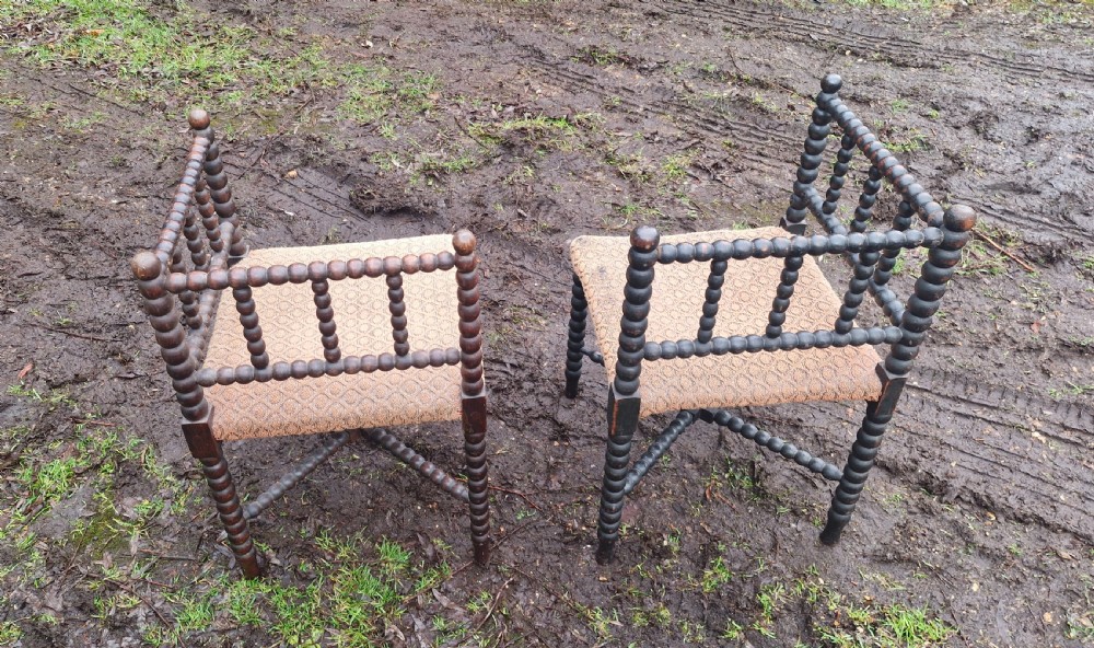 A pair of dark wood bobbin-turned corner chairs featuring patterned fabric seats and crossed lower stretchers. View V