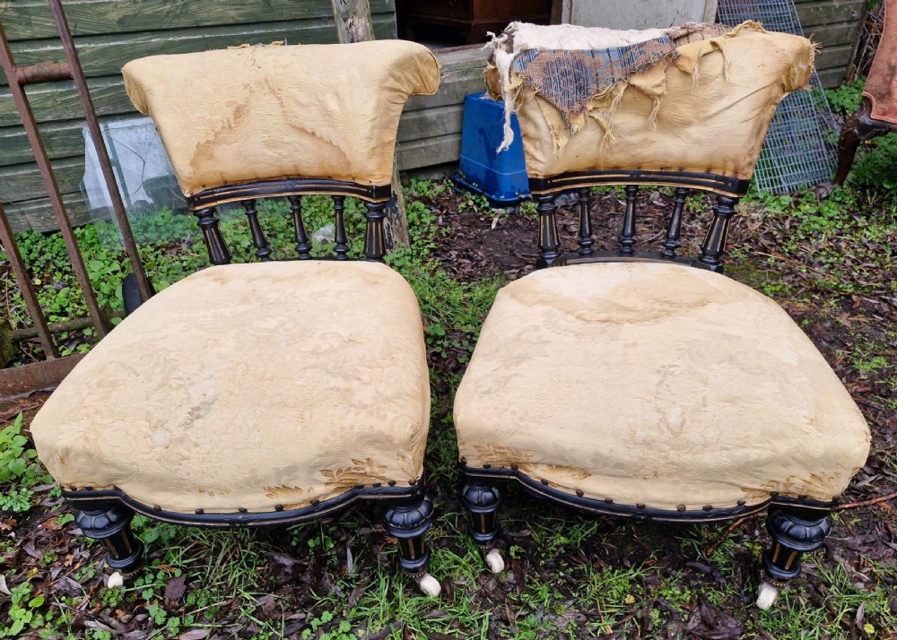 A pair of low Victorian ebonised nursing chairs with spindle backrests, turned front legs on ceramic castors, and worn yellow upholstery. View III
