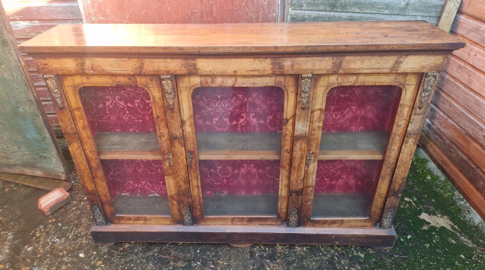 A nineteenth-century Victorian walnut side cabinet featuring three glazed glass doors with brass mounts and a red fabric lined interior. View II