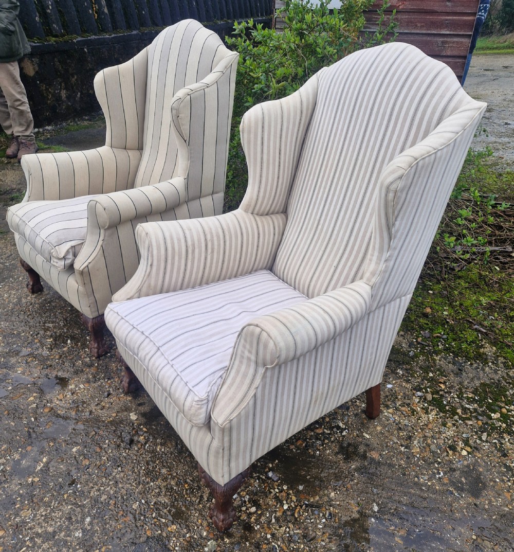 A pair of high-backed upholstered wingback armchairs featuring striped beige fabric and carved wooden cabriole legs with ball and claw feet. View V