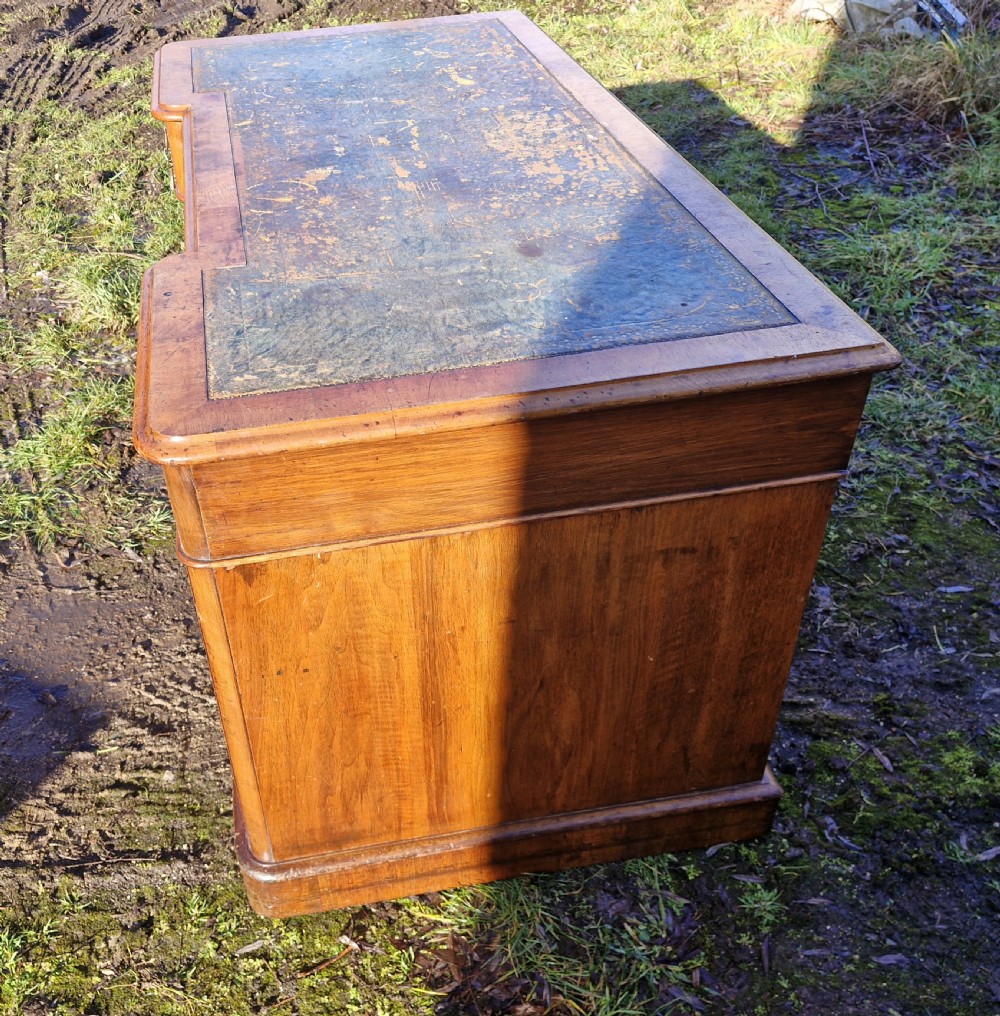 A Victorian walnut breakfront pedestal desk with a distressed green leather inset top and brass drop handles. View VIII