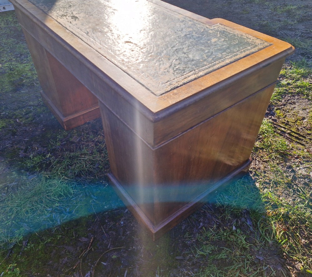 A Victorian walnut breakfront pedestal desk with a distressed green leather inset top and brass drop handles. View X