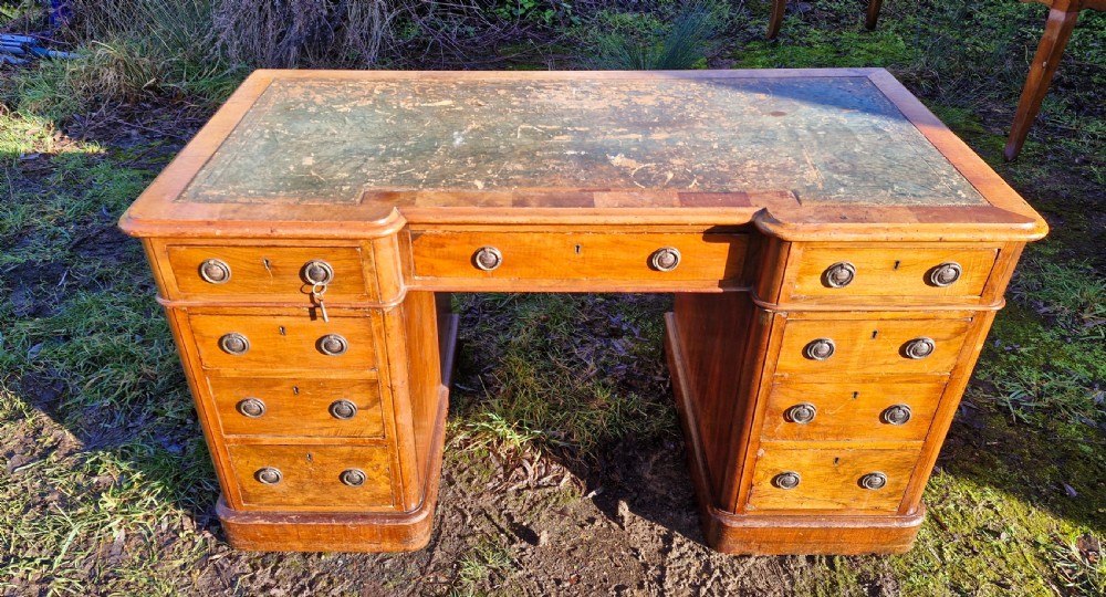 A Victorian walnut breakfront pedestal desk with a distressed green leather inset top and brass drop handles. View XI