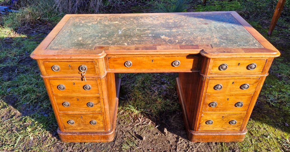 A Victorian walnut breakfront pedestal desk with a distressed green leather inset top and brass drop handles. View XII