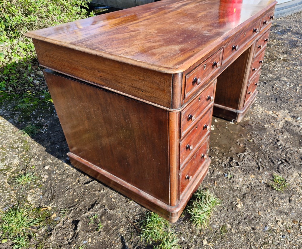 A Victorian mahogany pedestal writing desk with three top frieze drawers over twin pedestals, turned wooden knobs, and a plinth base. View II