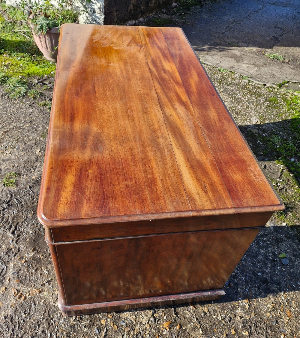 A Victorian mahogany pedestal writing desk with three top frieze drawers over twin pedestals, turned wooden knobs, and a plinth base. View III