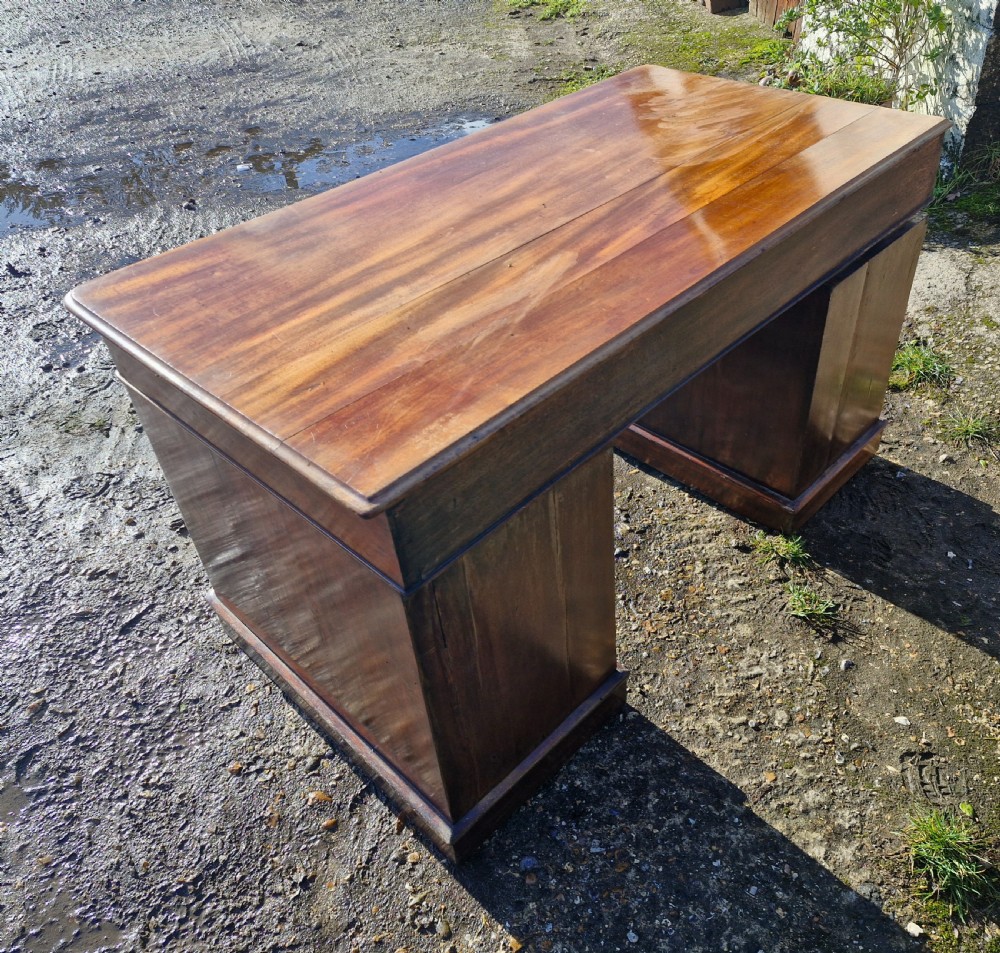 A Victorian mahogany pedestal writing desk with three top frieze drawers over twin pedestals, turned wooden knobs, and a plinth base. View IV