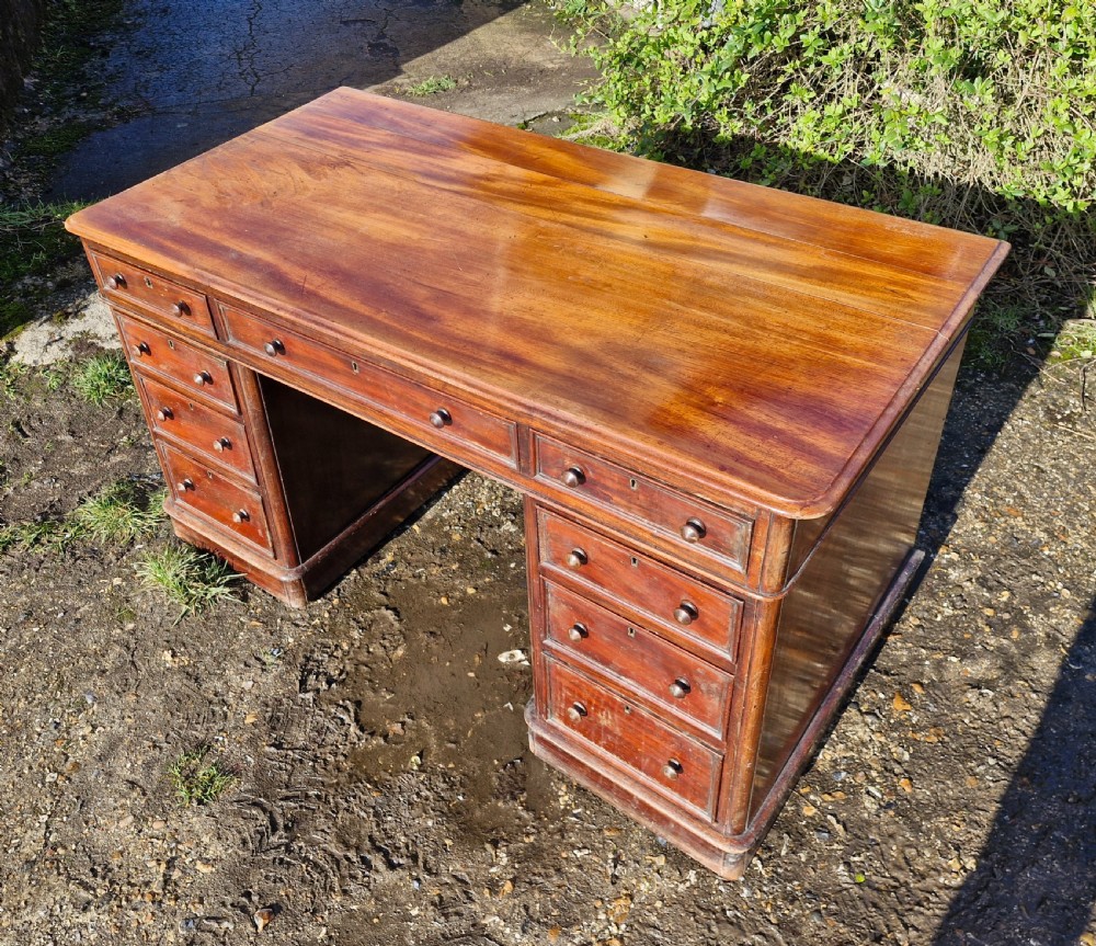 A Victorian mahogany pedestal writing desk with three top frieze drawers over twin pedestals, turned wooden knobs, and a plinth base. View VIII