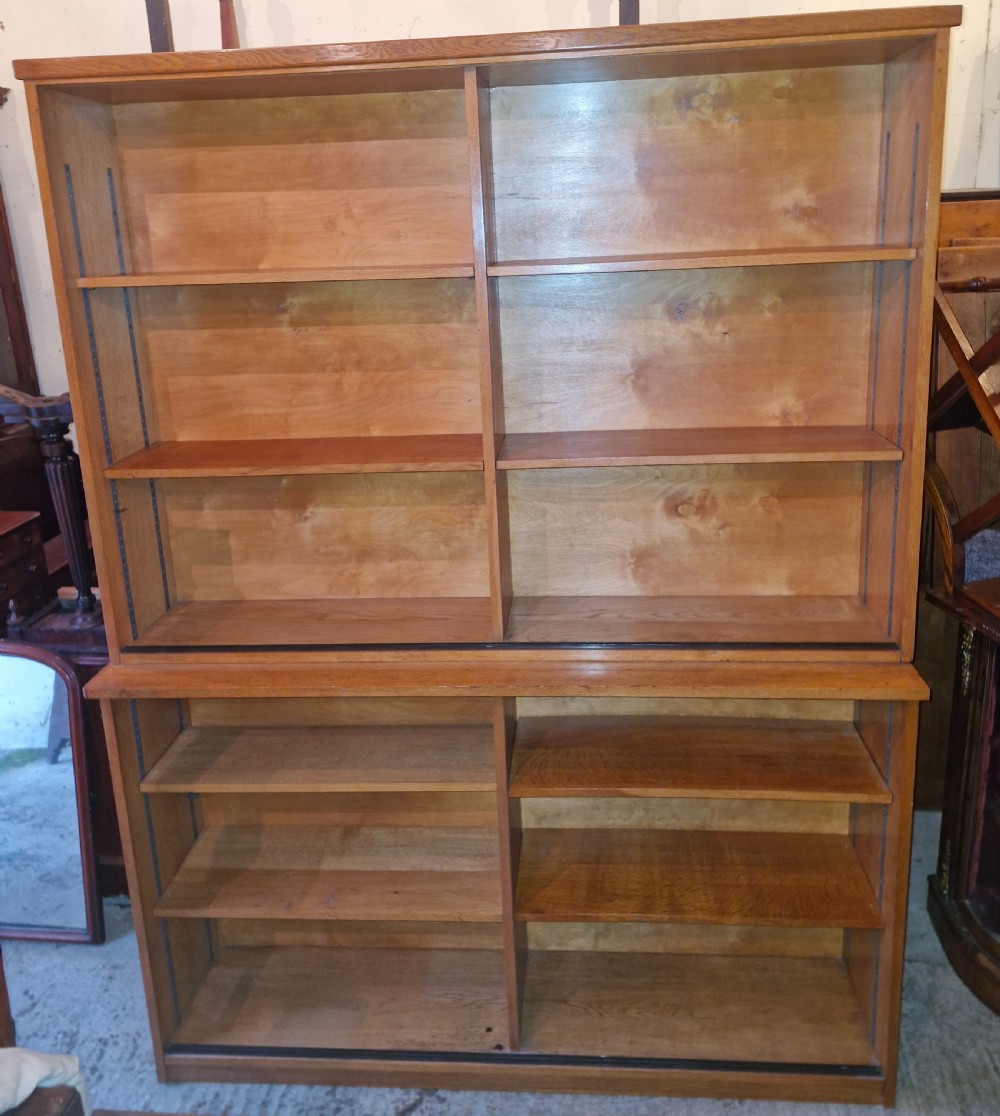 A tall open-front warm brown oak bookcase featuring two vertical columns with multiple adjustable wooden shelves.