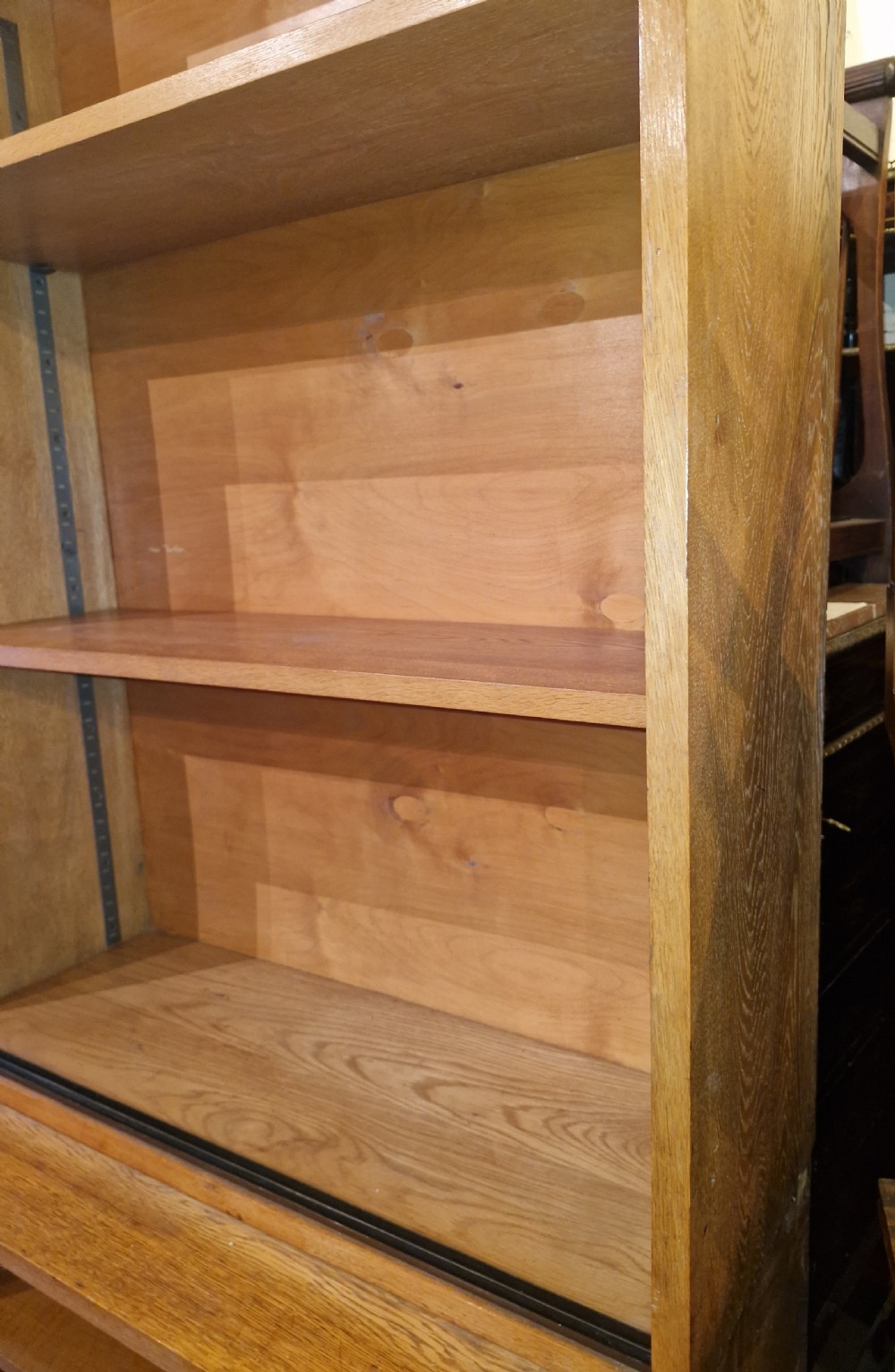 A tall open-front warm brown oak bookcase featuring two vertical columns with multiple adjustable wooden shelves. View IV