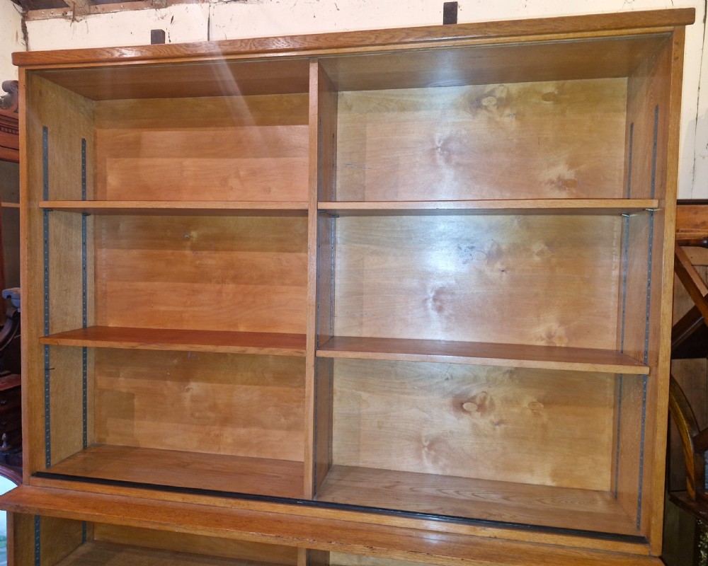 A tall open-front warm brown oak bookcase featuring two vertical columns with multiple adjustable wooden shelves. View V