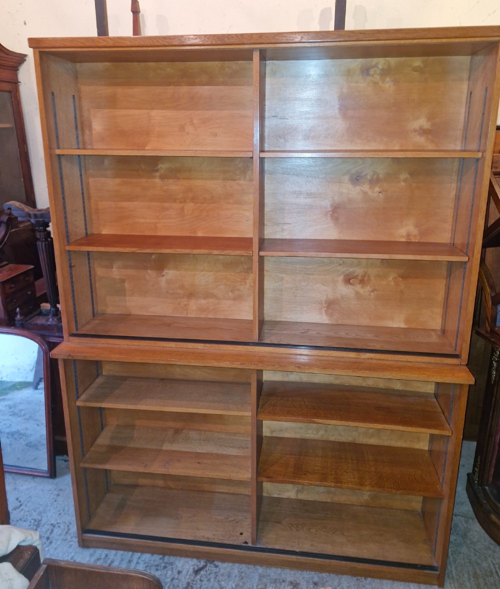 A tall open-front warm brown oak bookcase featuring two vertical columns with multiple adjustable wooden shelves. View VI