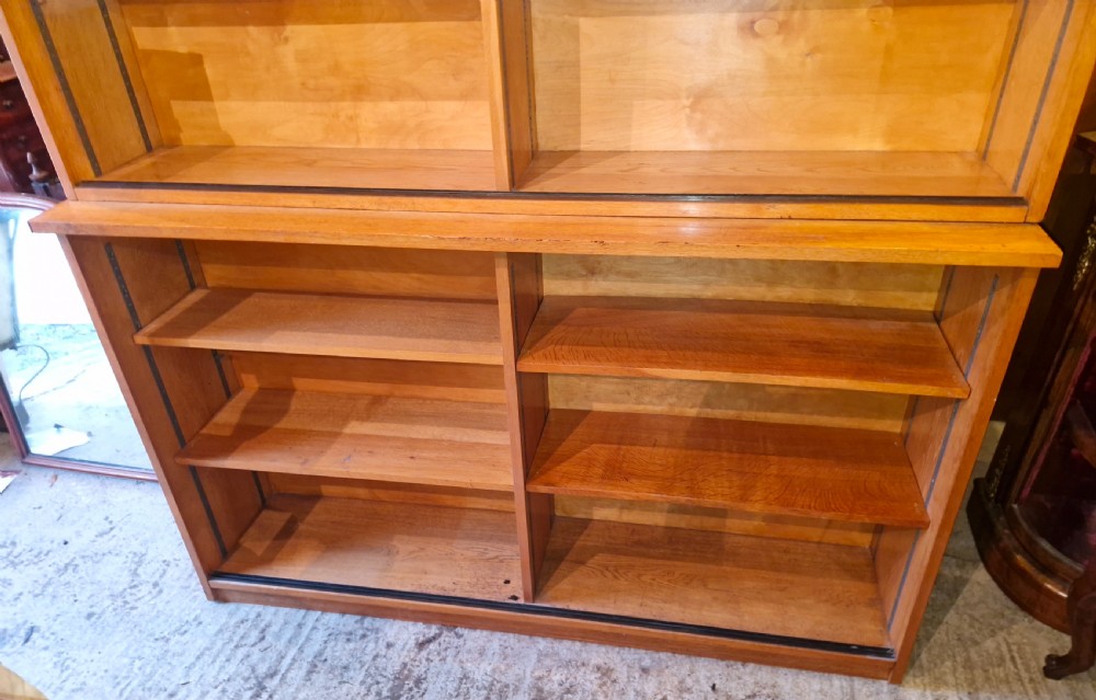 A tall open-front warm brown oak bookcase featuring two vertical columns with multiple adjustable wooden shelves. View VII