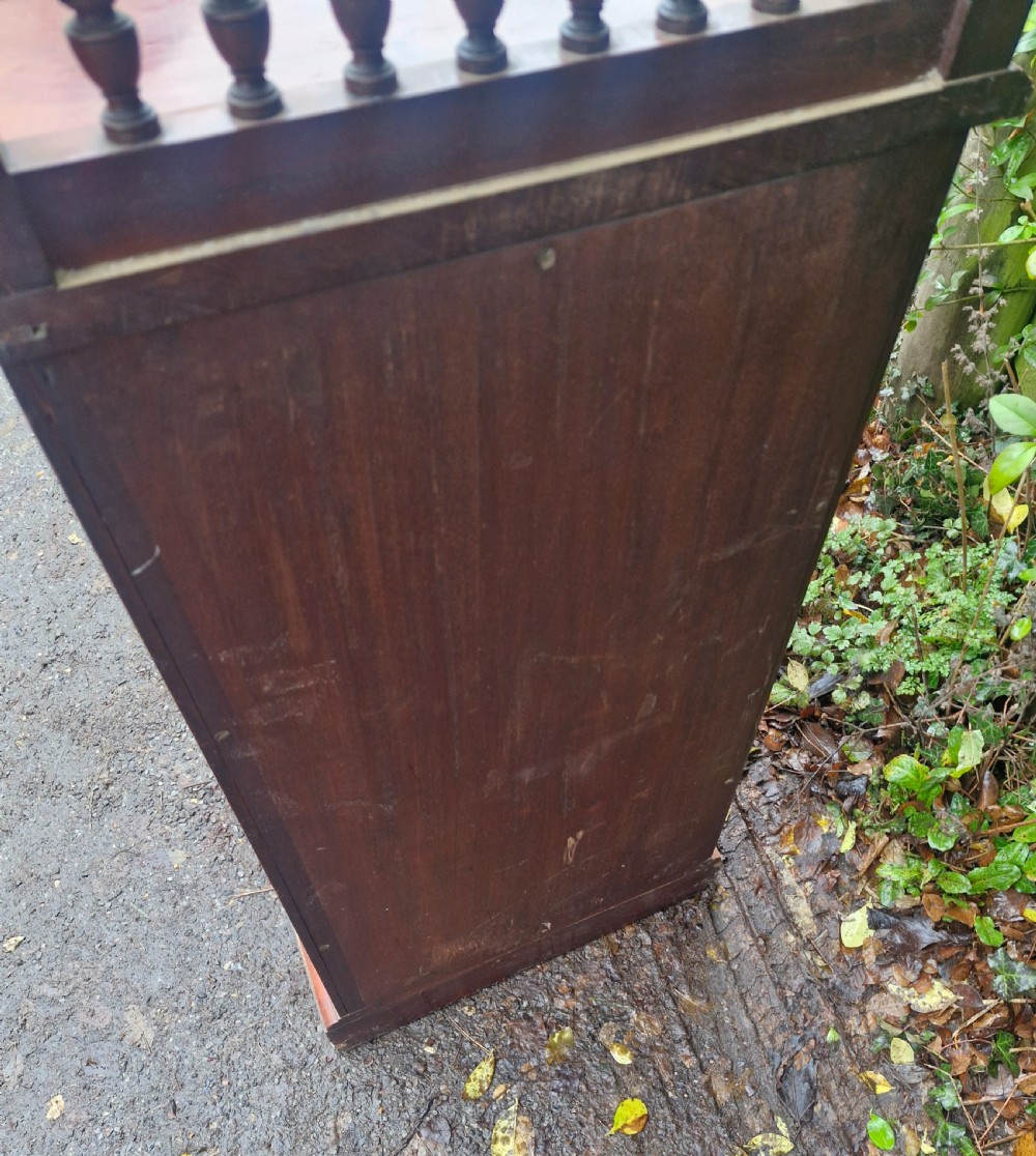 A late Victorian mahogany bedside cabinet featuring a spindle gallery top, a carved fielded door panel, and a brass latch. View III