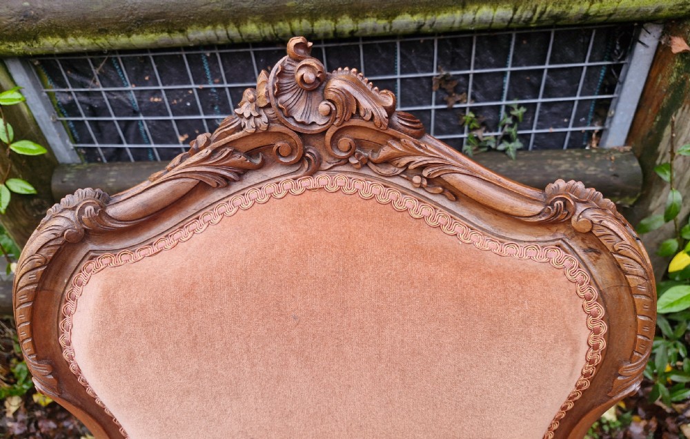 A pair of French Louis XV style carved walnut fauteuil armchairs with open padded armrests and peach velvet upholstery. View II