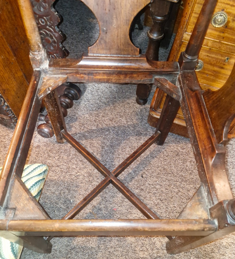 A late Georgian dark walnut corner chair featuring a curved continuous armrest, shaped splats, turned supports, and a green flame-stitch pattern drop-in seat. View V