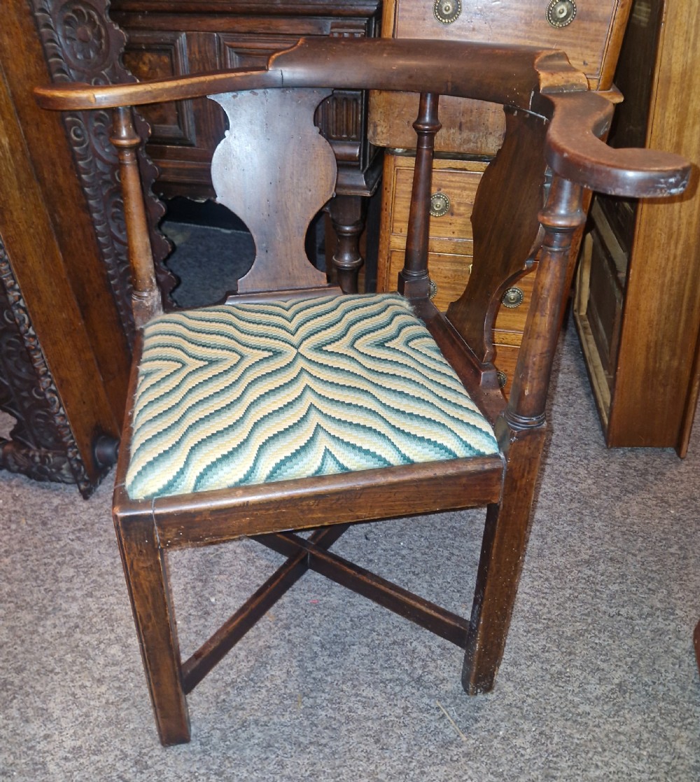 A late Georgian dark walnut corner chair featuring a curved continuous armrest, shaped splats, turned supports, and a green flame-stitch pattern drop-in seat. View VIII
