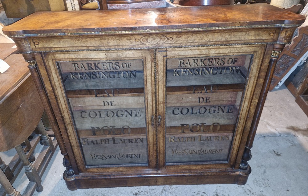 A Victorian inlaid walnut two-door side cabinet featuring glazed doors with stencilled lettering, decorative marquetry frieze, and brass mounts. View XII