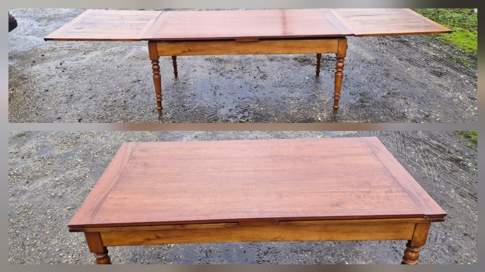A large French extending dining table made from warm brown wood, featuring two draw-out leaves and turned legs.
