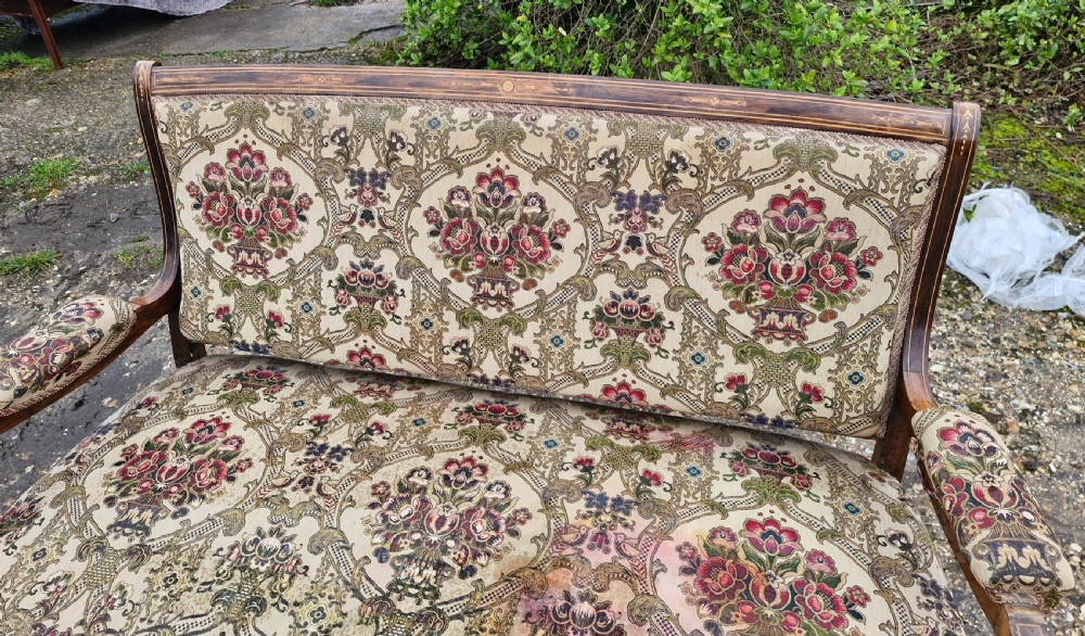 A late Victorian rosewood settee featuring delicate marquetry inlay, patterned upholstery, padded armrests, and turned legs on brass castors. View III