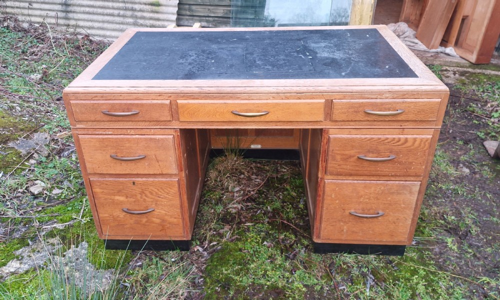 An Art Deco oak pedestal office desk featuring a dark inset writing top, streamlined drawers, and metal pull handles. View II