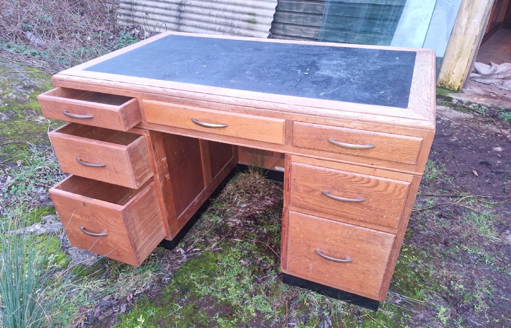 An Art Deco oak pedestal office desk featuring a dark inset writing top, streamlined drawers, and metal pull handles. View VII