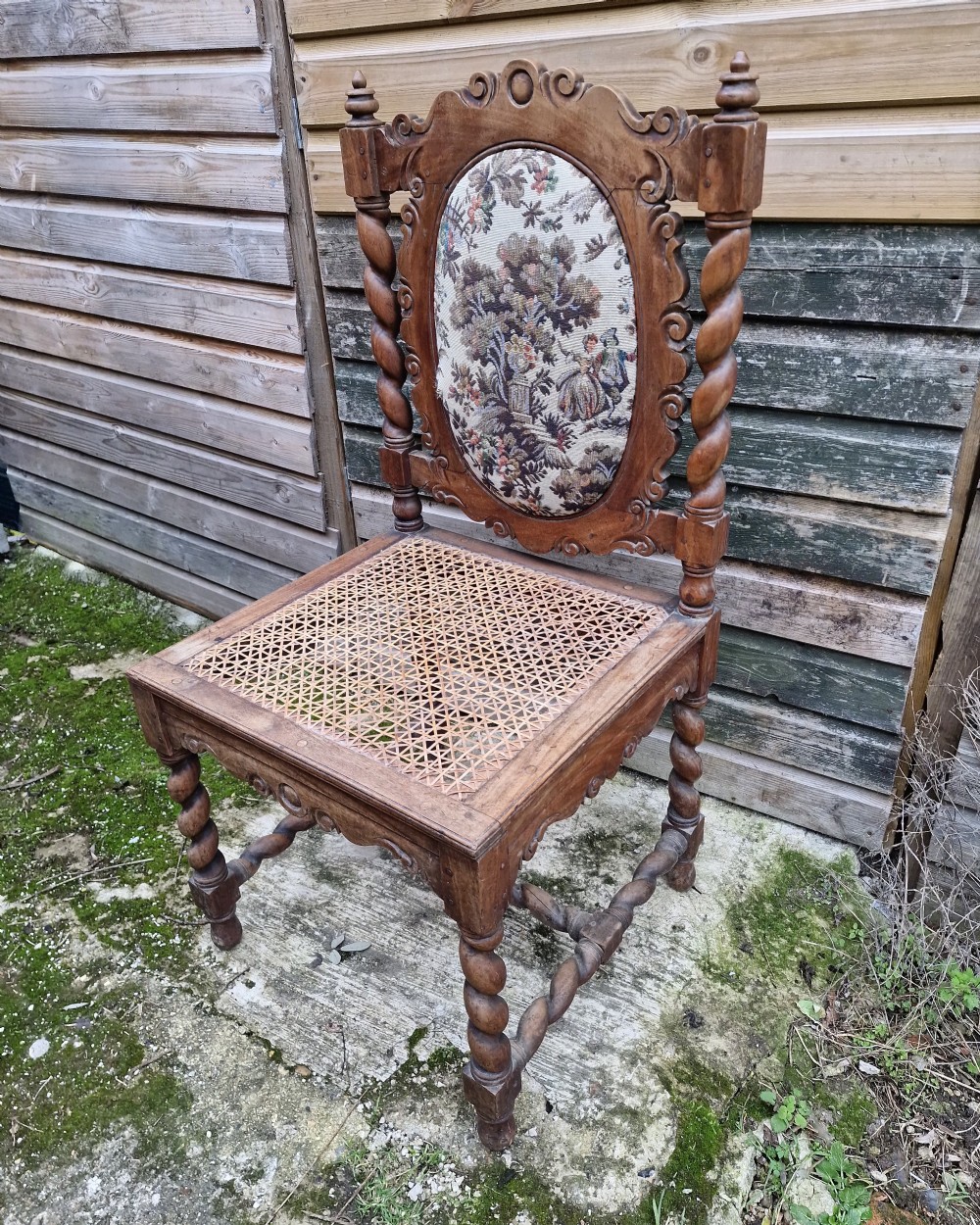 A late 19th-century carved satinwood hall chair featuring barley twist supports, a woven cane seat, and an oval tapestry back panel.