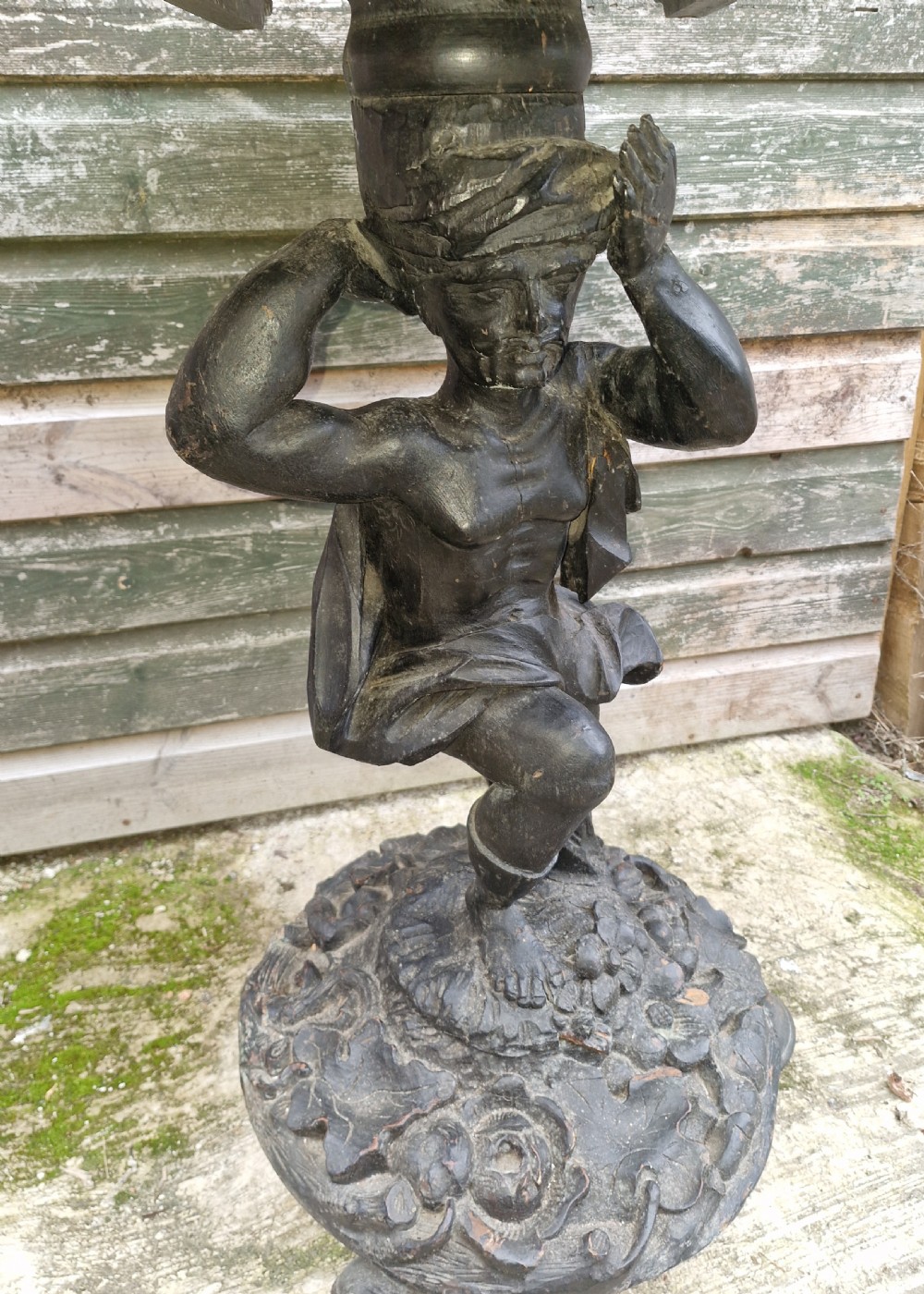 A carved ebonised wooden occasional table featuring a figural pedestal base supporting a circular top with a leaf-carved border. View III