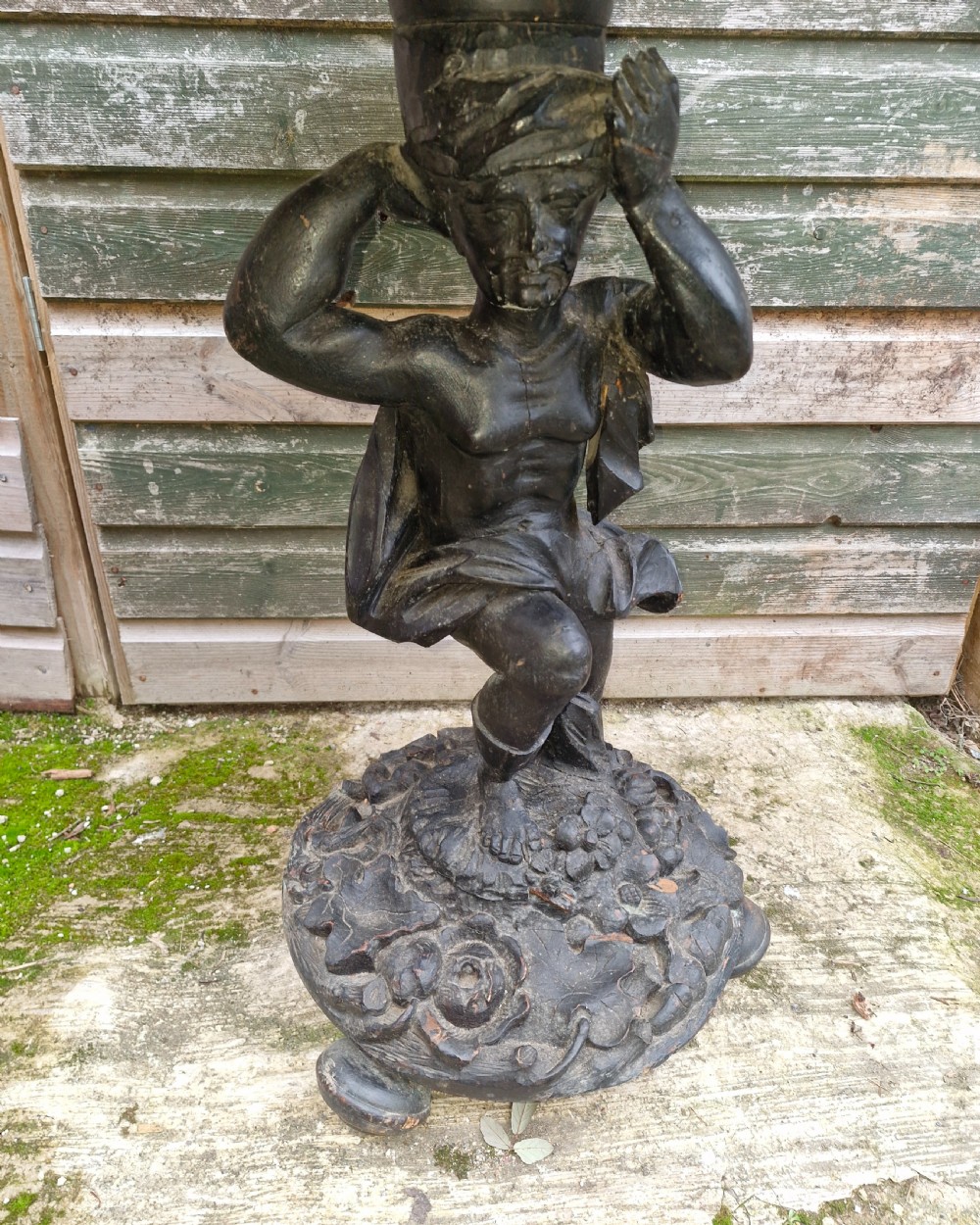 A carved ebonised wooden occasional table featuring a figural pedestal base supporting a circular top with a leaf-carved border. View V